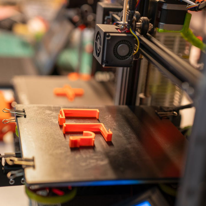 Oranje onderdelen worden geprint op het bed van een 3D printer