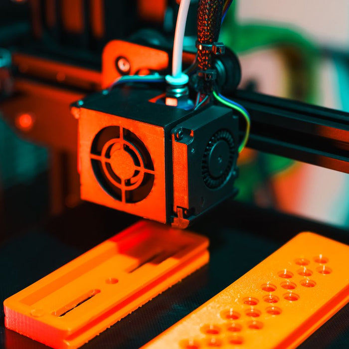 Oranje geprinte onderdelen onder een printkop