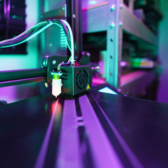 Een 3D printer aan het werk in gekleurd licht